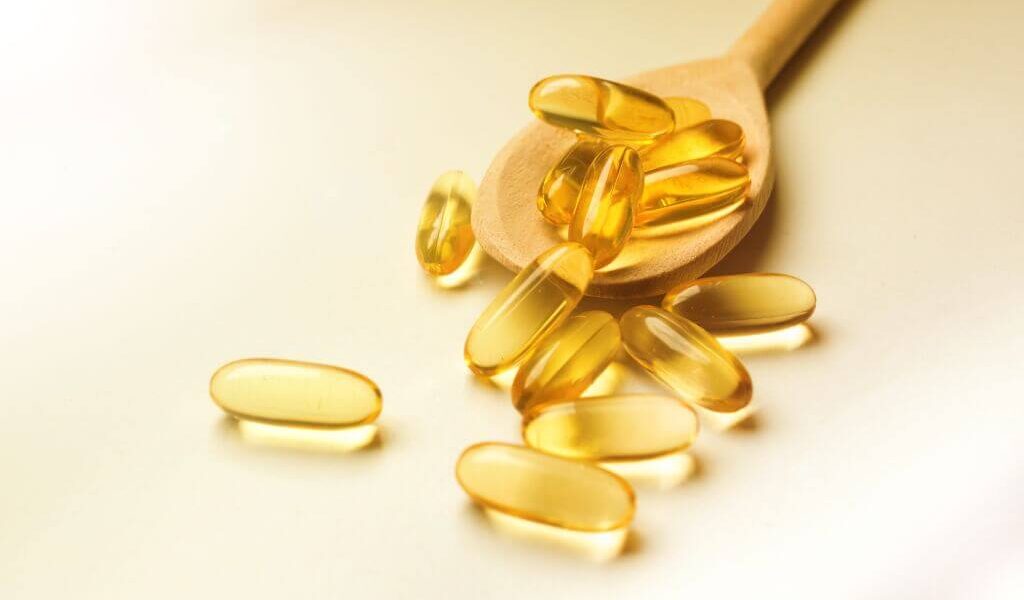 Wooden spoon full of fish oil supplement capsules